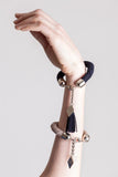 The no. 11 edition of the handcuff bracelet is made of navy blue suede with galvanized metal components with leather tassel. Silver edition.