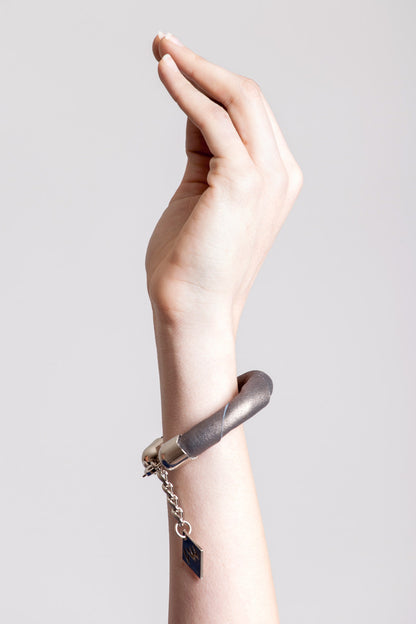 The no. 14 edition of the handcuff bracelet is made of leather in copper color with galvanized metal components. Silver edition.