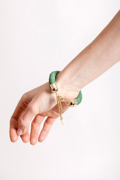 The no. 18 edition of the handcuff bracelet is made of green suede with galvanized metal components. Gold edition.