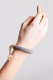 The no. 3 edition of the handcuff bracelet is made of anthracite gray suede with galvanized metal components and quartz. Gold edition.