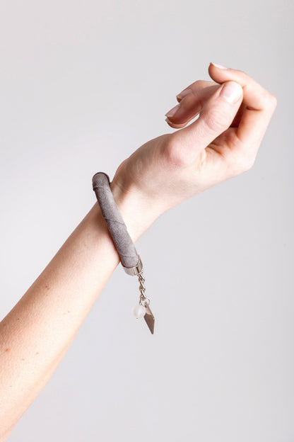 The no. 3 edition of the handcuff bracelet is made of anthracite gray suede with galvanized metal components and quartz. Silver edition.