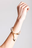 The no. 5 edition of the handcuff bracelet is made of beige suede with galvanized metal components without leather tassel. Gold edition.