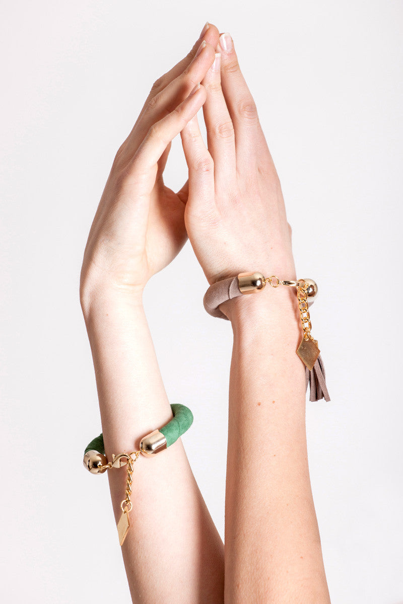 The no. 5 edition of the handcuff bracelet is made of beige suede with galvanized metal components with leather tassel. Gold edition.