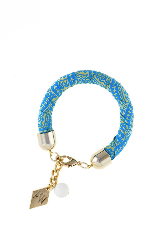 The no. 3 edition of the handcuff pattern bracelet is made of african batik cotton with galvanized metal components and white coral. Gold edition.