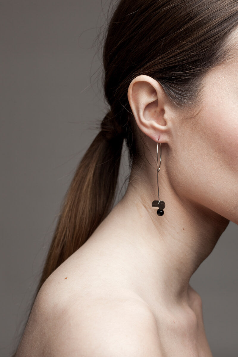 This pair of earring is made of a hoop earring which features galvanized brass and detachable pendant made of brass galvanized in silver and onyx.