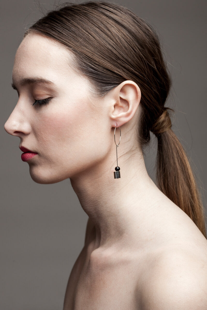 This pair of earring is made of a hoop earring which features galvanized brass and detachable pendant made of brass galvanized in silver and onyx.