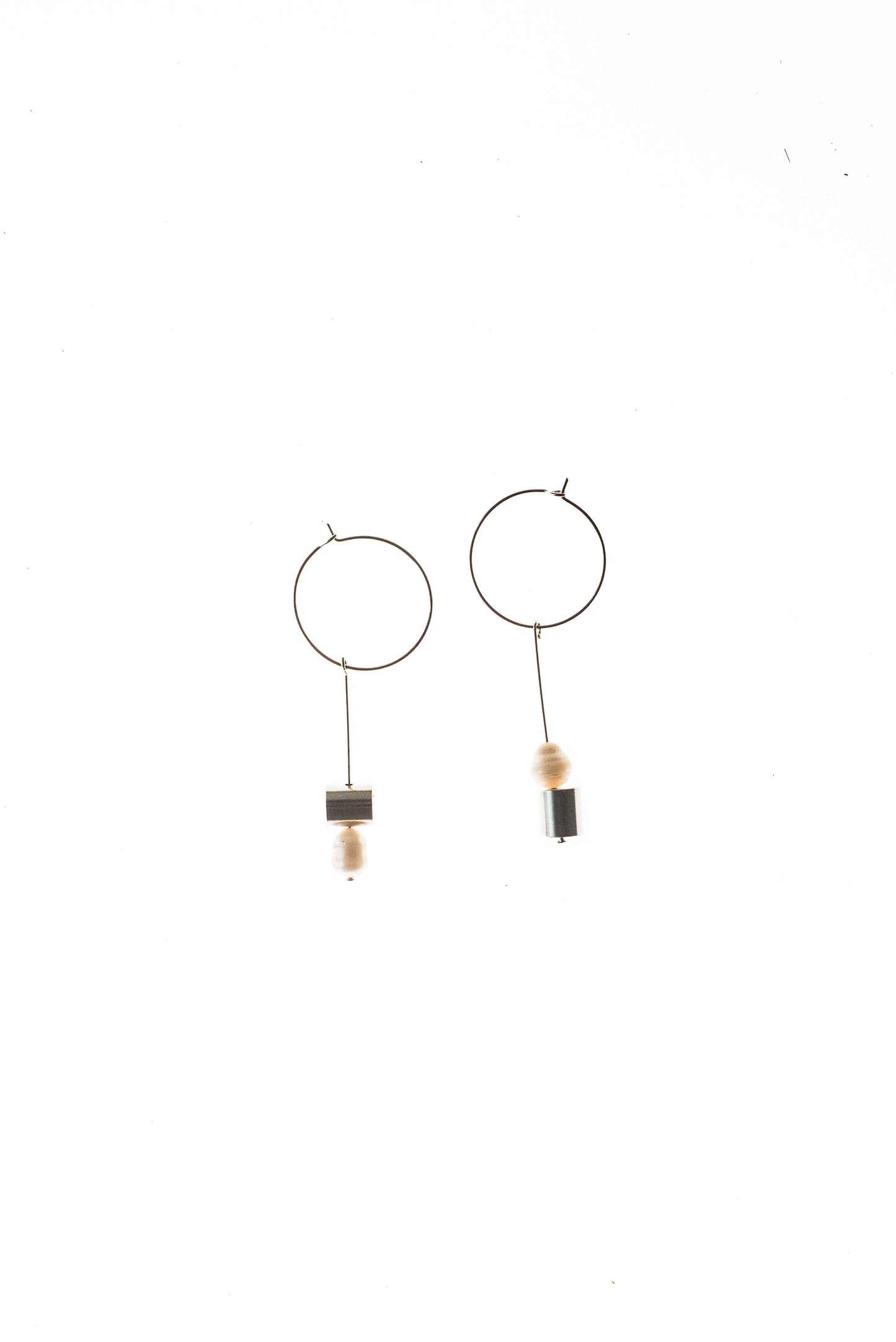 This pair of earring is made of a hoop earring which features galvanized brass and detachable pendant made of brass galvanized in silver and freshwater pearl.