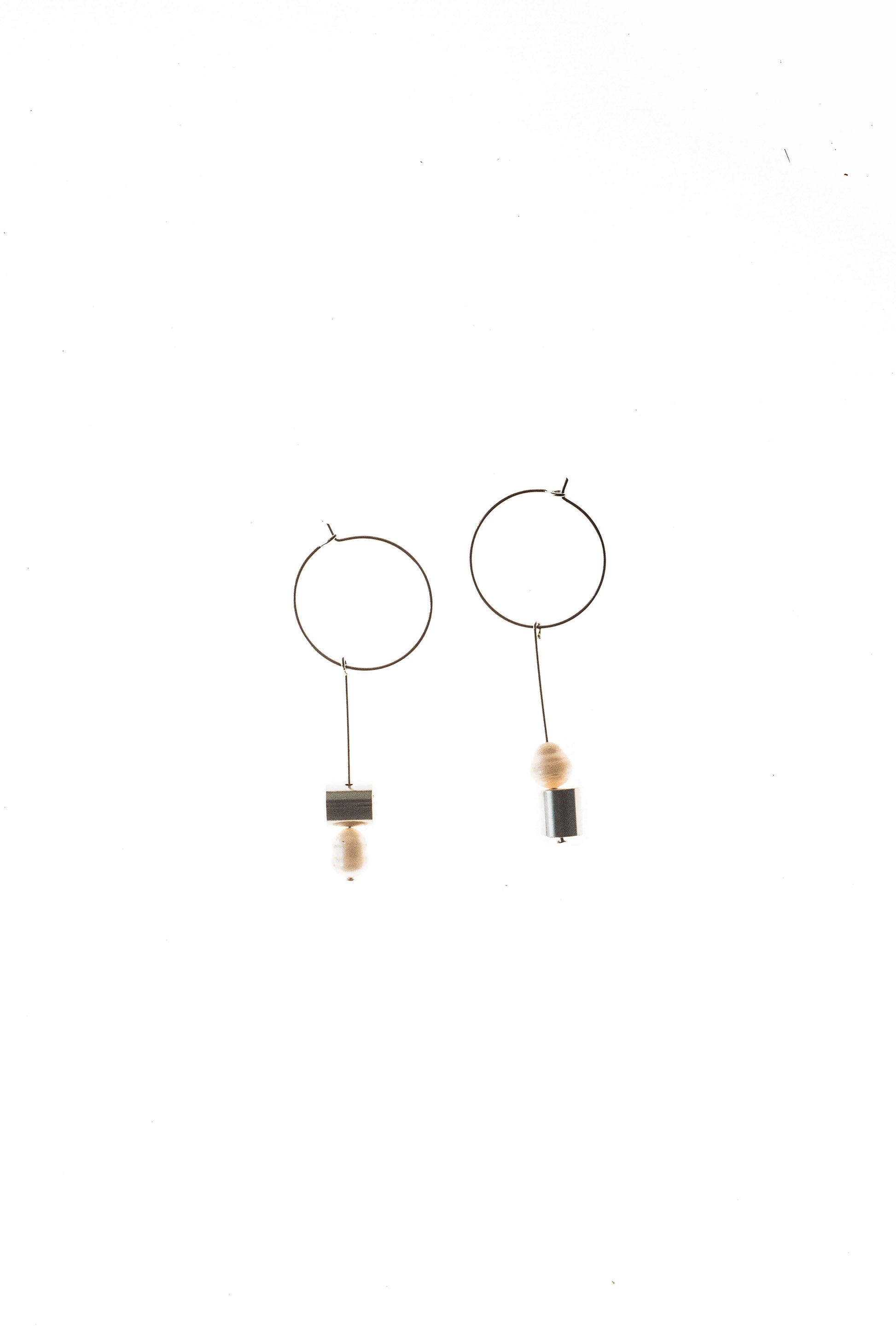 This pair of earring is made of a hoop earring which features galvanized brass and detachable pendant made of brass galvanized in silver and freshwater pearl.