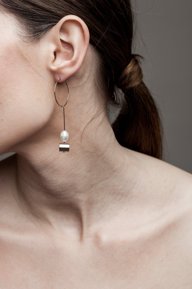 This pair of earring is made of a hoop earring which features galvanized brass and detachable pendant made of brass galvanized in silver and freshwater pearl.
