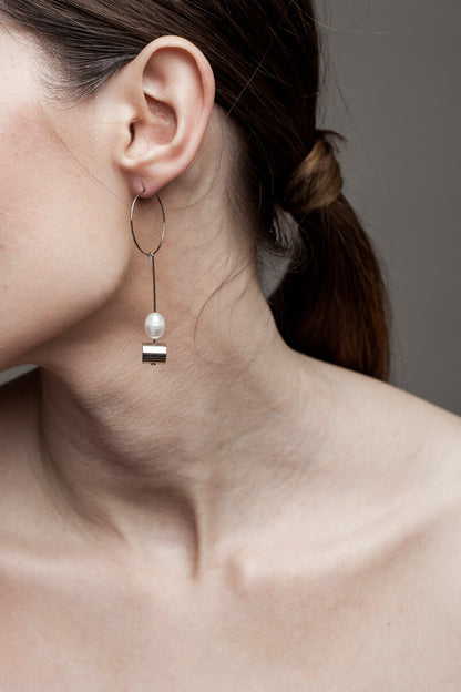 This pair of earring is made of a hoop earring which features galvanized brass and detachable pendant made of brass galvanized in silver and freshwater pearl.